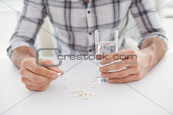 Casual businessman holding glass of water and tablet