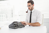 Hipster businessman using a typewriter smoking a pipe