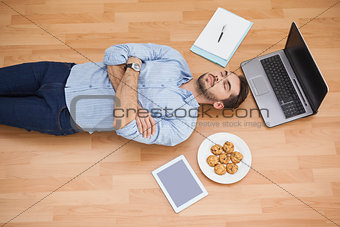 Casual man lying on floor surrounded by his possesions