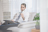Businessman shopping online on his couch seen through glass