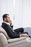 Smiling businessman making a call on his couch