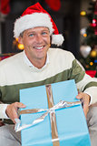 Smiling man in santa hat opening a gift
