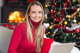 Smiling blonde woman using laptop on couch