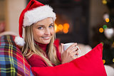 Smiling blonde wearing santa hat while holding a mug