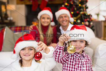 Cute little siblings wearing santa hat holding baubles