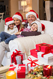 Festive family in santa hat hugging on couch