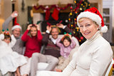 Smiling grandmother in santa hat with her family behind