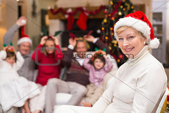 Smiling grandmother in santa hat with her family behind