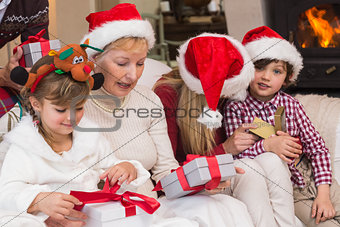 Happy extended family opening gifts on the couch
