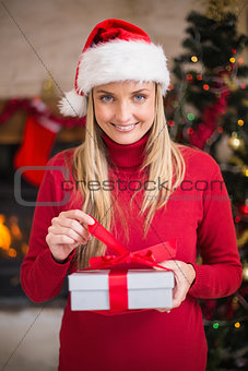 Smiling woman in santa hat opening a gift