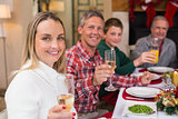 Smiling family toasting to camera during christmas dinner