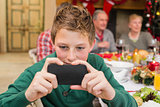 Young boy holding smartphone during christmas dinner