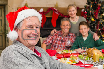 Smiling grandfather in santa hat posing in front of his family