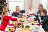 Family pulling christmas crackers at the dinner table