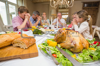 Family saying grace before christmas dinner together