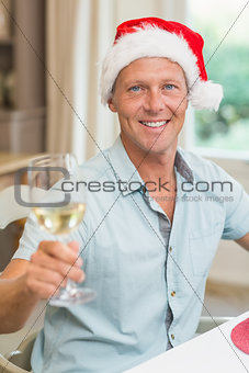 Handsome man in santa hat toasting with white wine