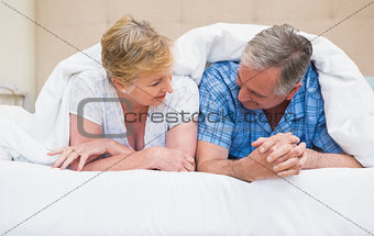 Senior couple smiling under the duvet
