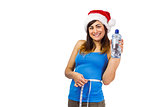 Festive fit brunette measuring her waist and holding bottle
