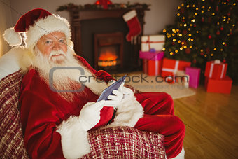 Happy santa using tablet on the couch