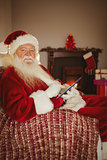 Cheerful santa touching tablet on the couch