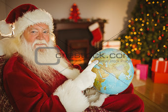 Smiling santa pointing his finger on the globe