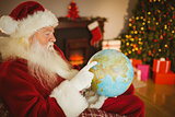 Santa claus pointing his finger on the globe
