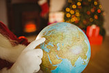 Close up of santa pointing his finger on the globe