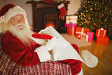 Smiling santa claus writing his list on scroll