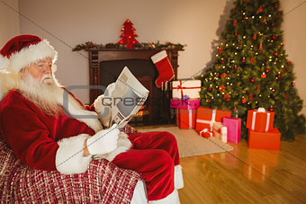Santa claus reading newspaper on the couch