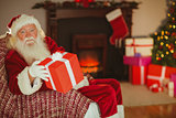 Cheerful santa claus offering a gift