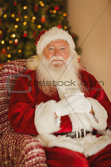 Happy santa relaxing on the armchair
