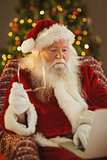 Santa holding his glasses and using laptop