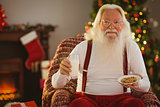 Santa holding glass of milk and plate with cookie
