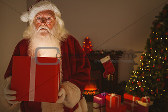 Surprised santa claus delivering a glowing gift