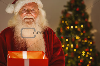 Happy santa holding a glowing gift