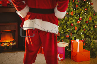 Mid section of santa standing in front of the christmas tree