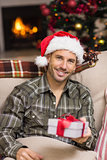 Smiling man in santa hat showing a gift