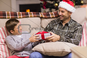 Son giving father a christmas gift on the couch