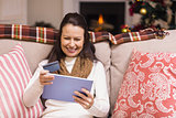 Festive brunette woman using her credit card and tablet pc