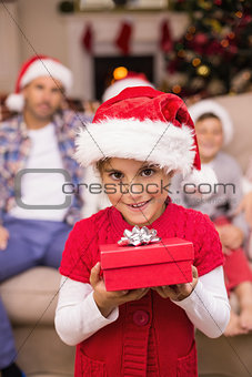 Smiling daughter holding gift in front of her family