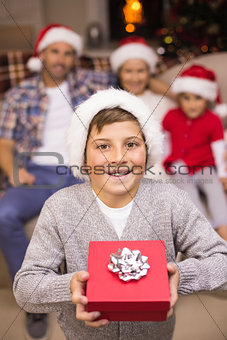 Festive son holding gift in front of his family