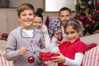 Smiling brother and sister holding gift and baubles