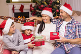 Festive family in santa hat exchanging gifts