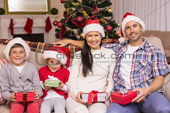 Festive family posing with gifts on the couch