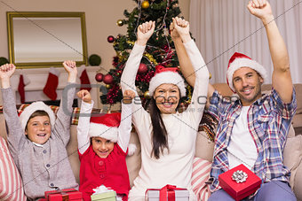 Festive family in santa hat cheering on the couch