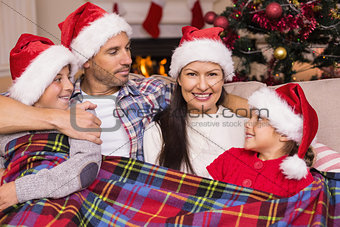 Festive family in santa hat hugging under the cover