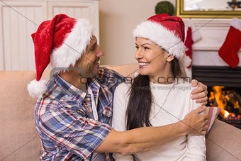 Festive couple in santa hat hugging on the couch