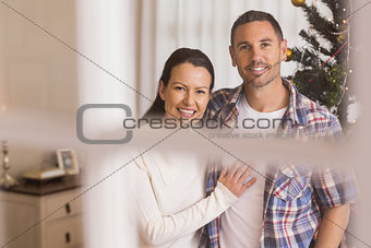 Smiling couple cuddling near the christmas tree