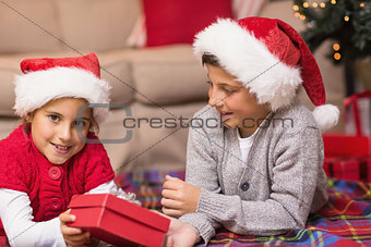 Brother and sister lying on the cover holding a gift