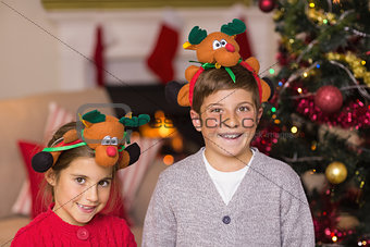 Happy brother and sister in headband near christmas tree